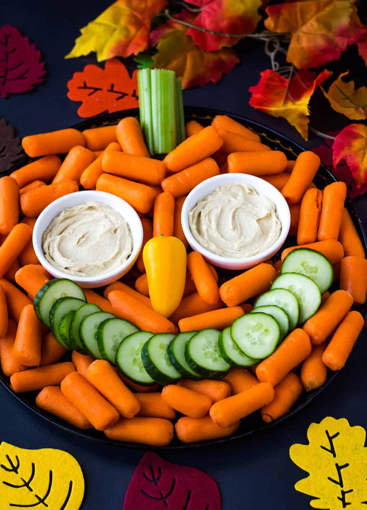 pumpkin face veggie tray surrounds by fall leaves