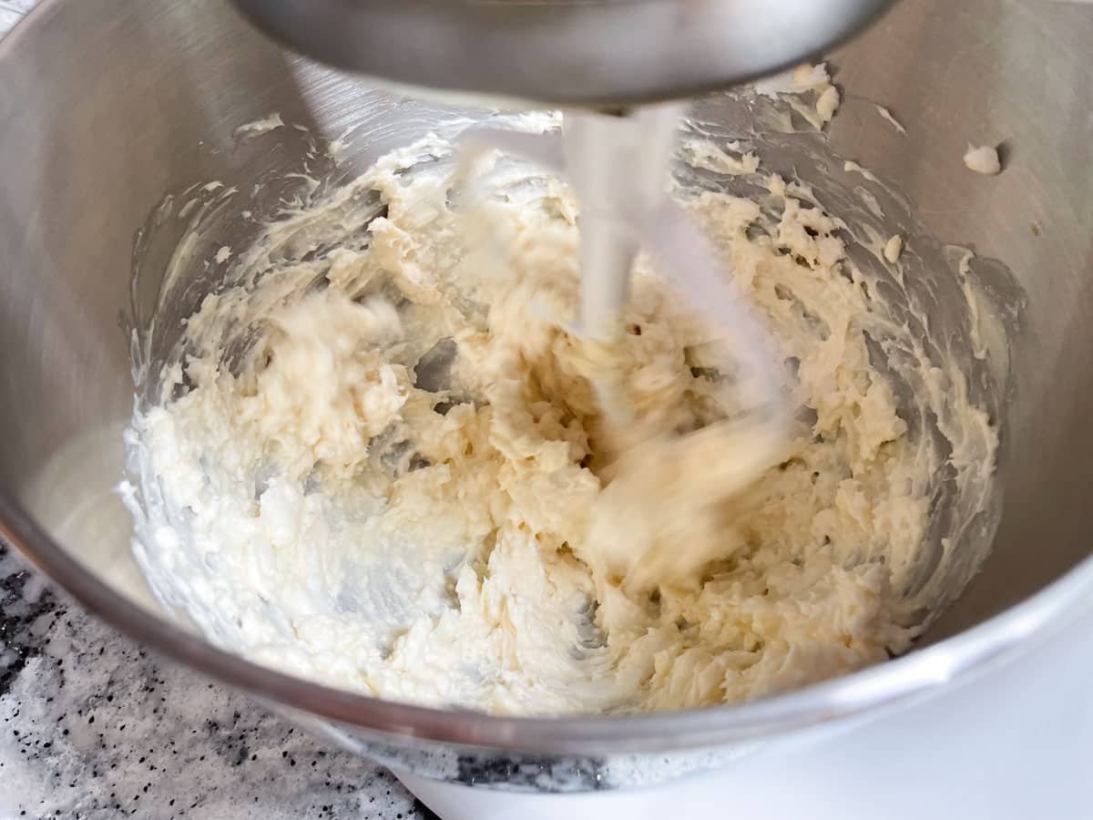 Cream cheese and butter beating together in stand-mixer.