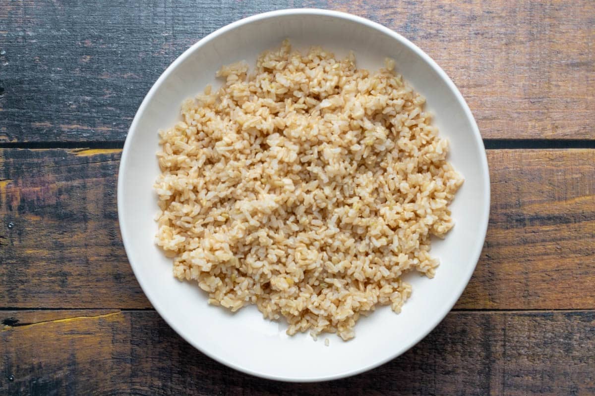 Cooked brown rice in white bowl.