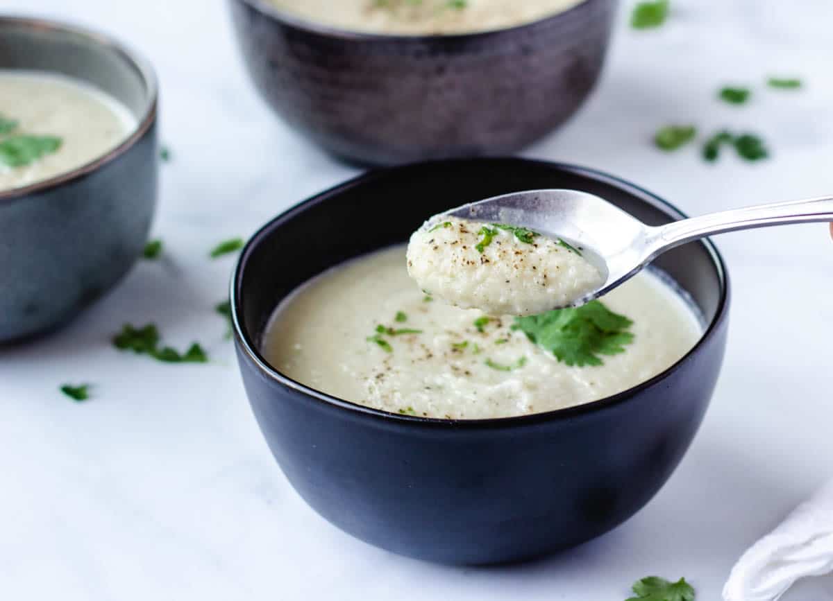 spoonful of cauliflower soup from black bowl