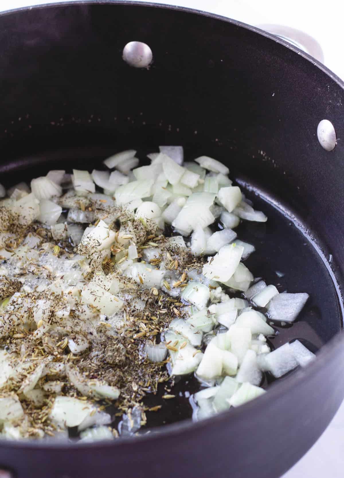 onions, garlic, and herbs in pan