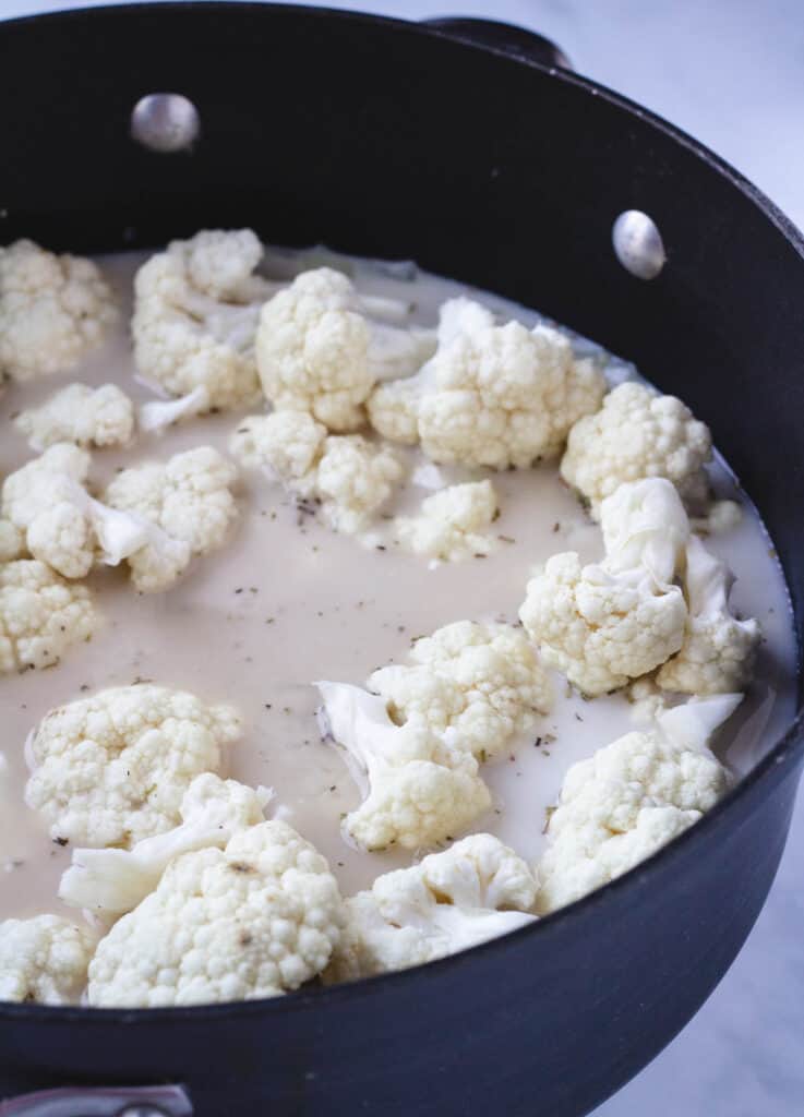 cauliflower florets covered with coconut milk and vegetable stock in pot