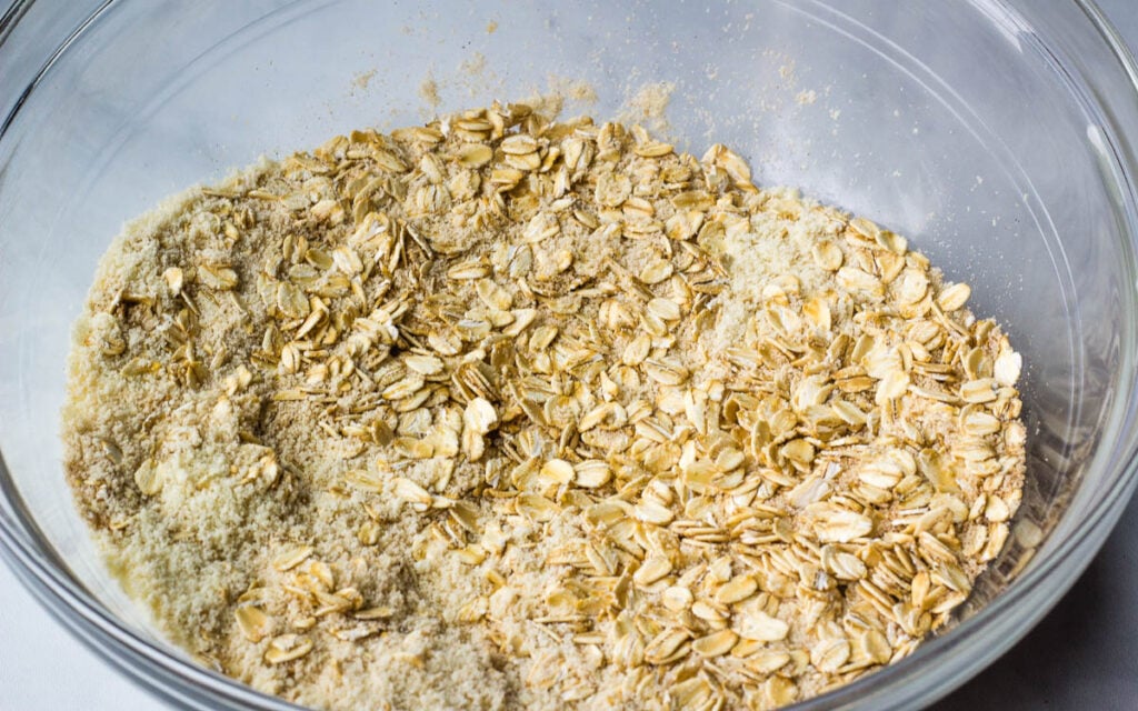 Oats and flour mixed together in glass bowl. 