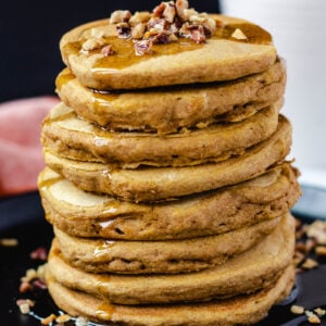 vegan pumpkin pancakes topped with nuts and syrup
