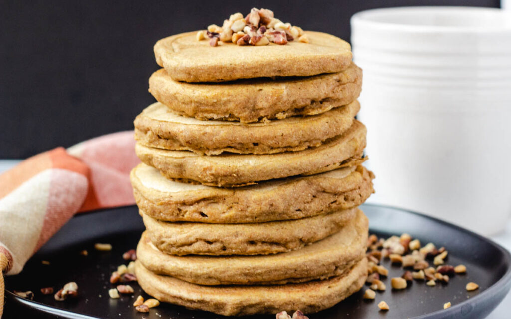 Stack of pancakes topped with nuts.