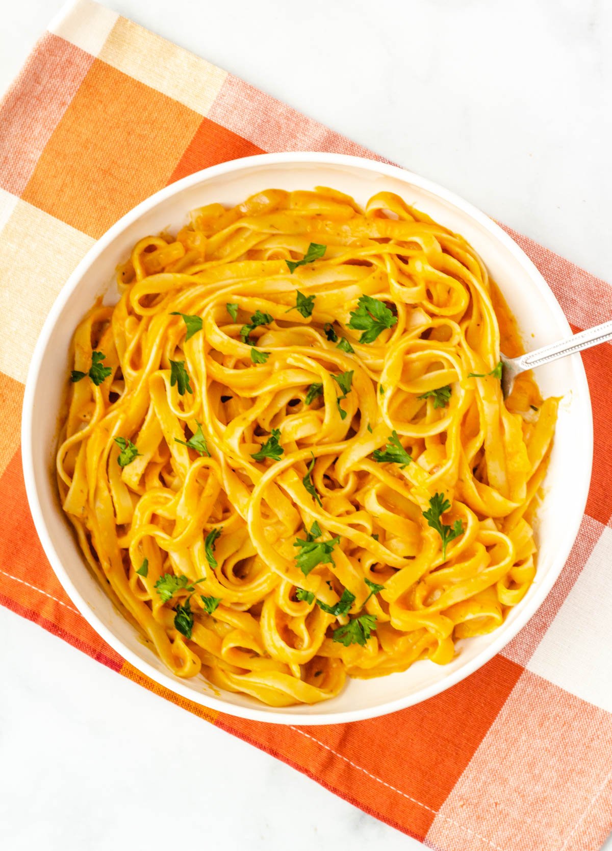 Linguine with pumpkin sauce in wide white bowl.
