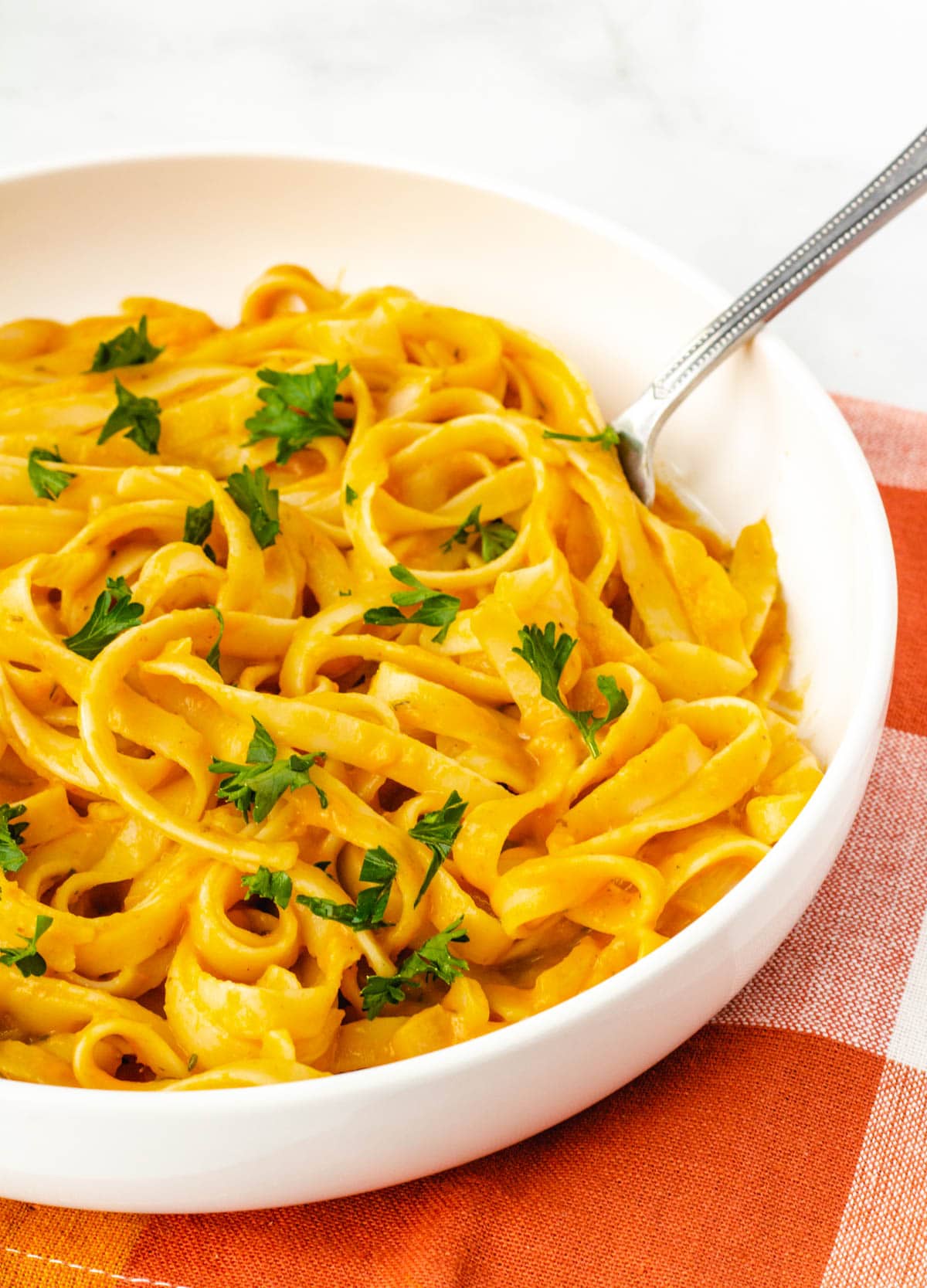 Pumpkin pasta in white bowl.