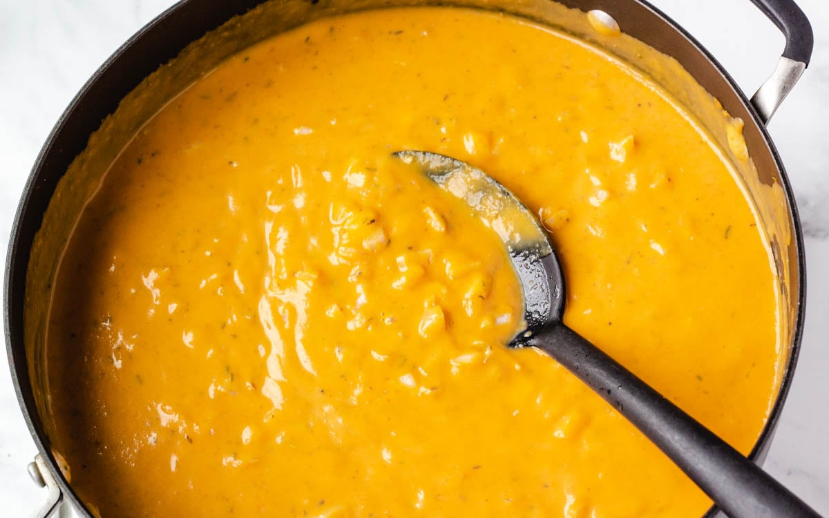 Creamy pumpkin pasta sauce in a pan with spoon.