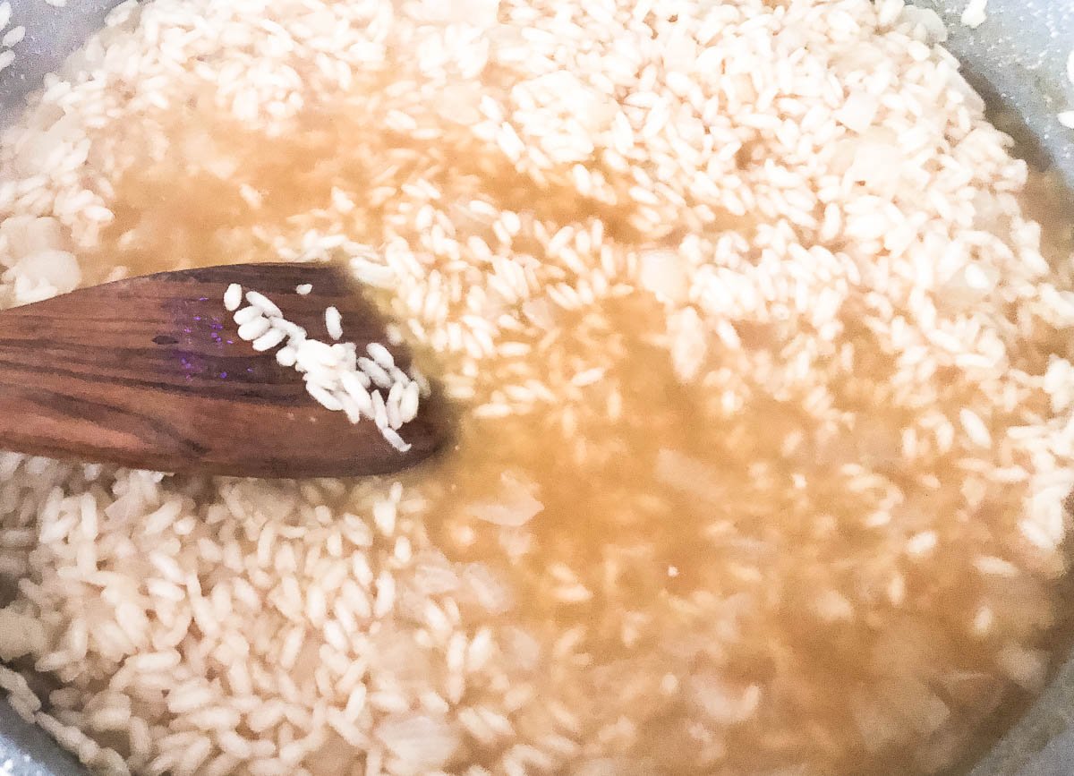Arborio rice and stock in pot.