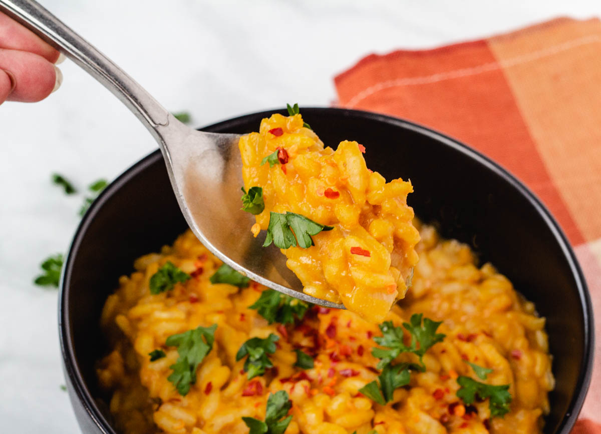 Spoon lifting from bowl of pumpkin risotto.