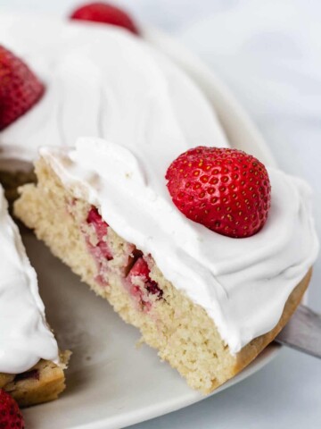 slice of strawberry cake topped with a fresh strawberry
