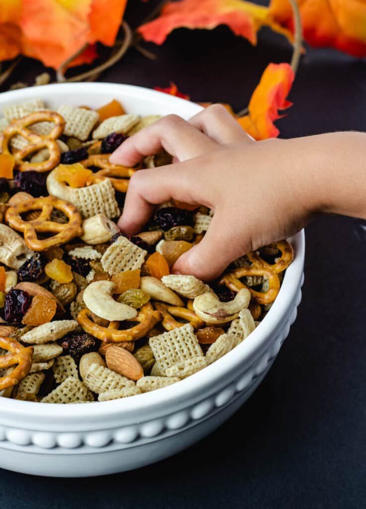 hand reaching for trail mix in white bowl