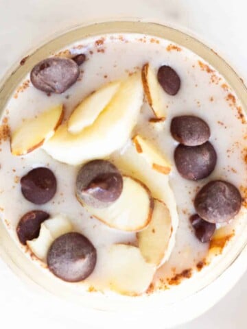 overhead of banana overnight oats topped with chocolate chips and almonds