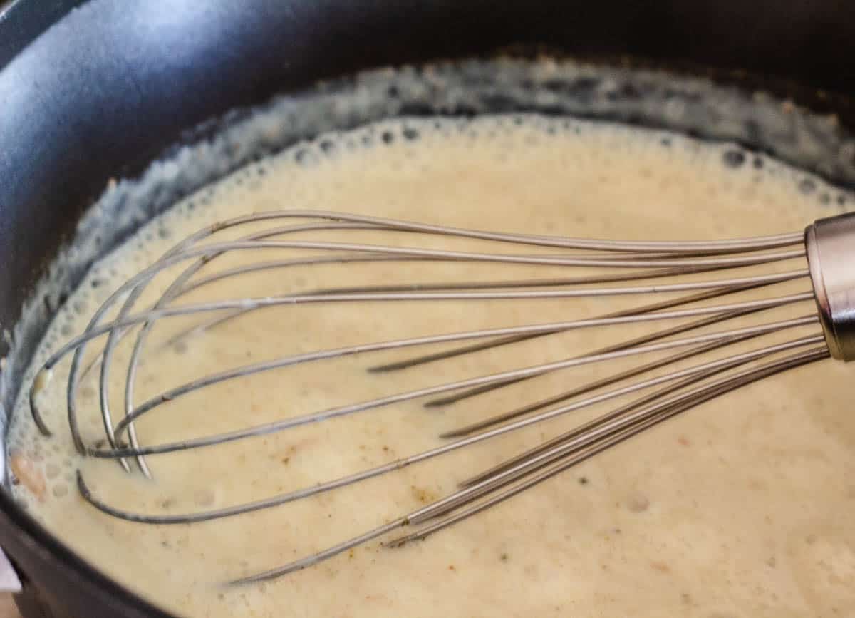 Cream sauce with whisk in saucepan.