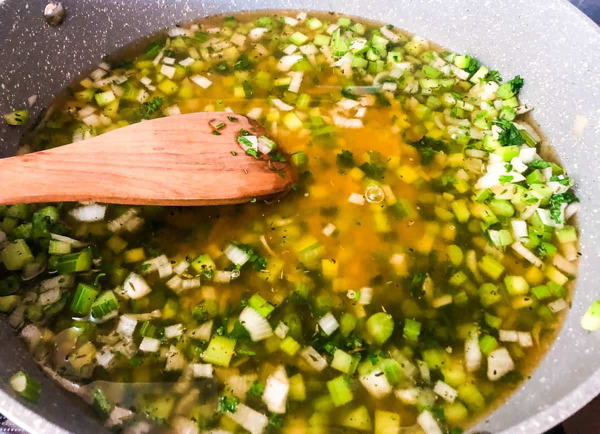 Vegetable stock in pot with onions and celery.
