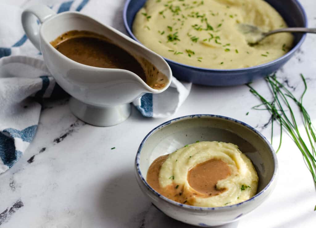 gravy in a gravy boat, and mashed potatoes in a bowl topped with gravy