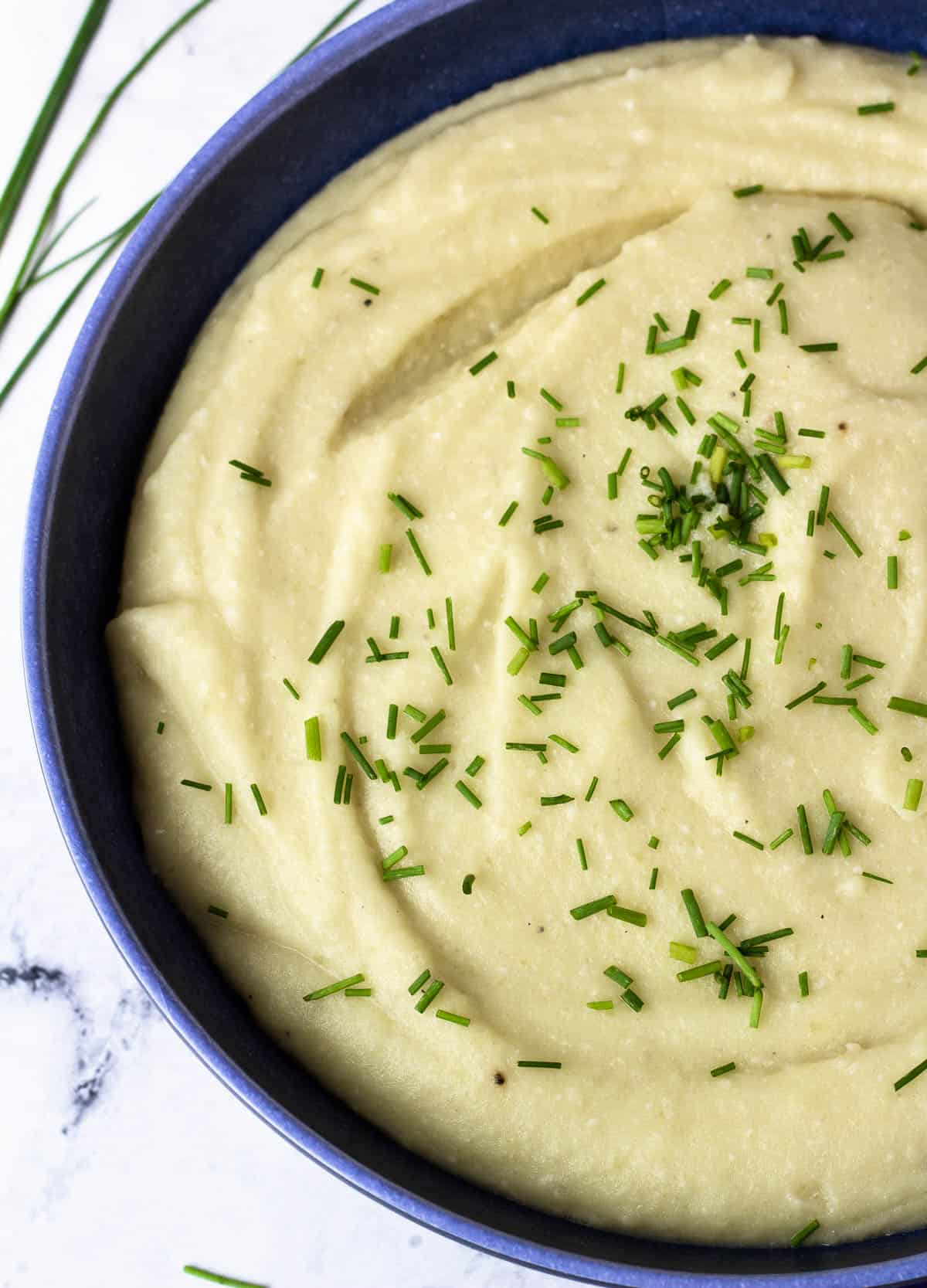 Mashed potatoes with almond milk in blue serving bowl.
