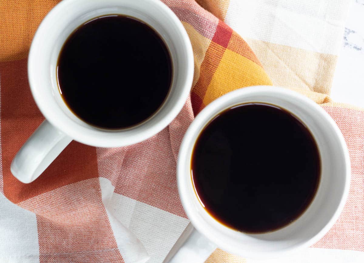 Two mugs filled with black coffee.

