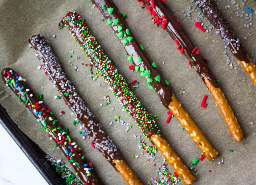 pretzels dipped in chocolate on baking sheet lined with parchment paper