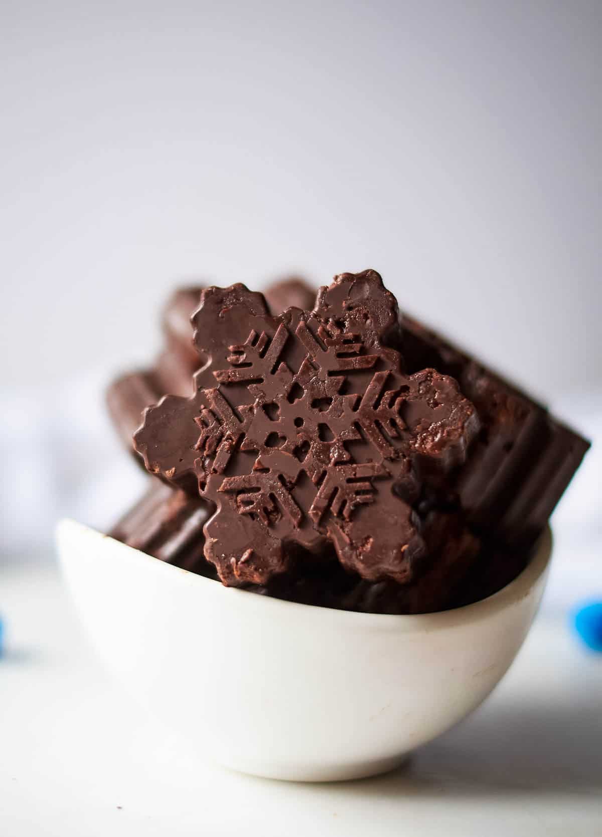 Dark chocolate snowflakes in white bowl.