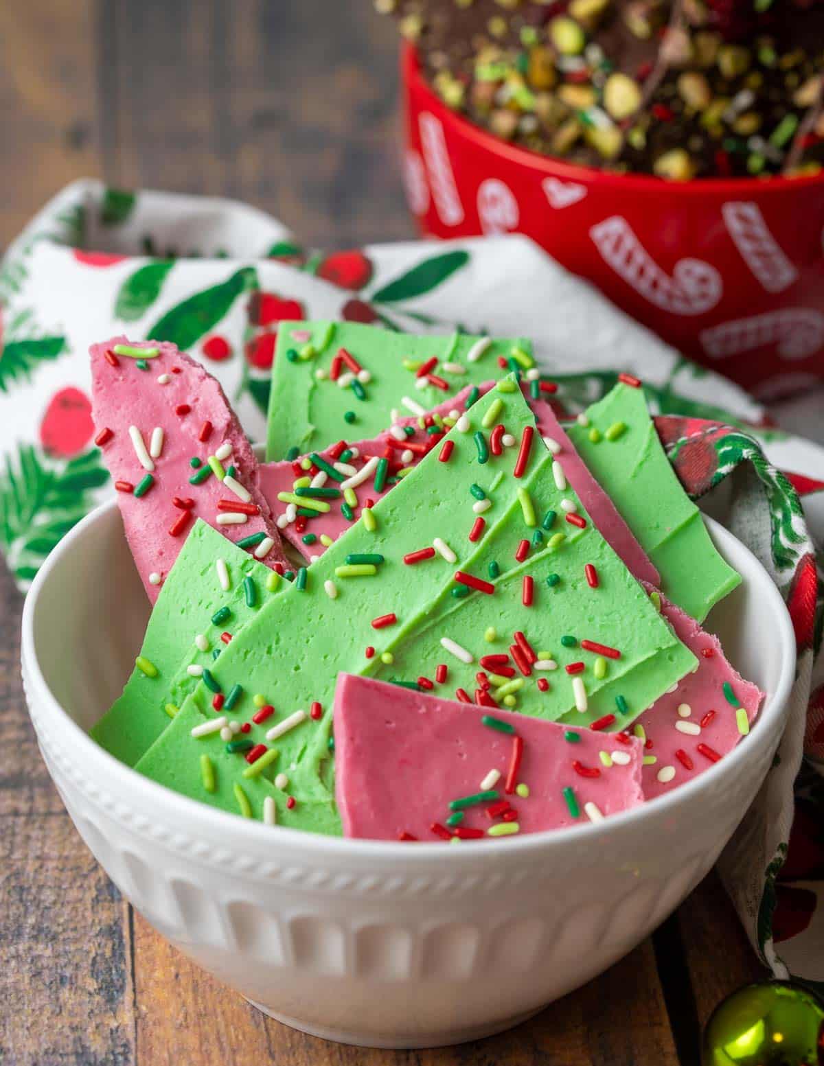 Christmas chocolate bark colored green and red with sprinkles in a white bowl.