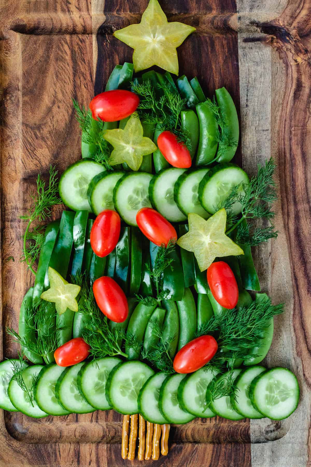 Christmas veggie tray with cucumber, green peppers, snap peas, tomatoes, dill, and starfruit