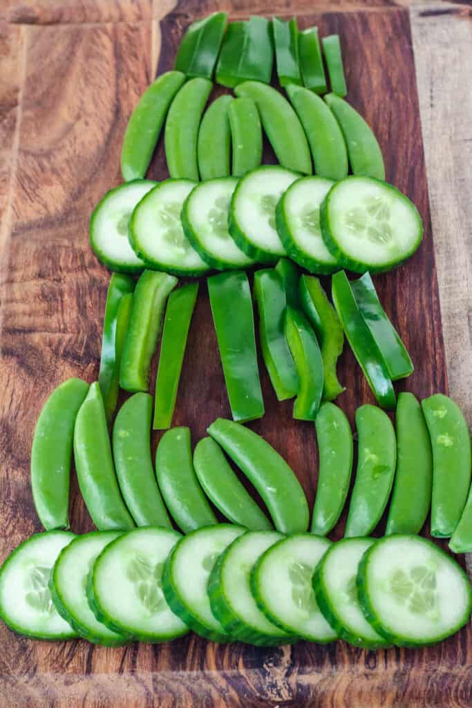 cucumbers, snap peas, and green pepper slices arranges in rows to look like a pine tree
