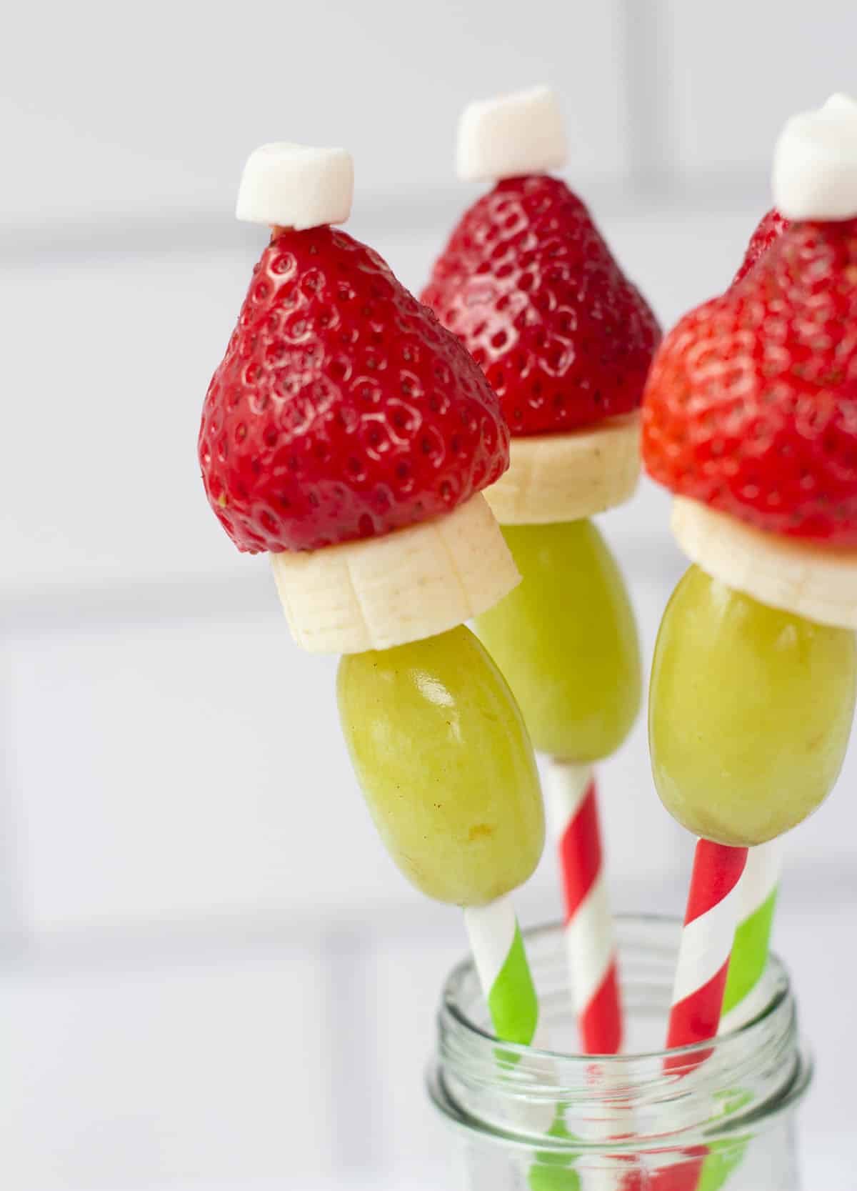 holiday fruit skewers made to look like the grinch with green grapes, banana, strawberry and a marshmallow puff