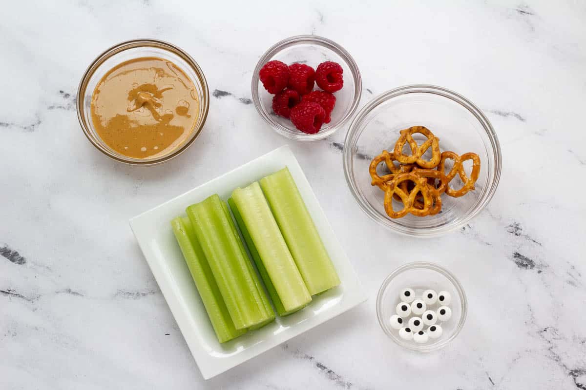 Reindeer Celery Stick ingredients: peanut butter, raspberries, pretzels, celery sticks, and candy eyes. 
