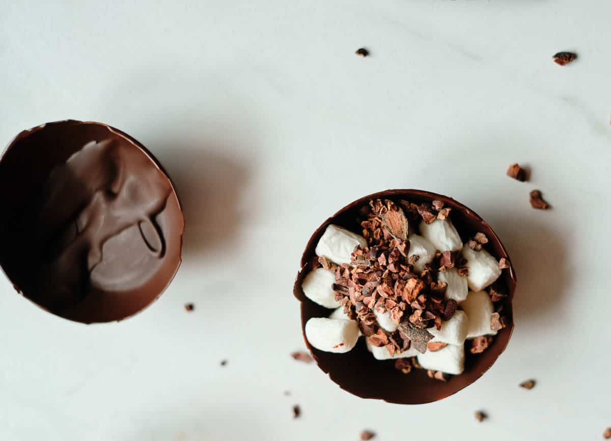 chocolate half sphere filled with marshmallows and cacao nibs