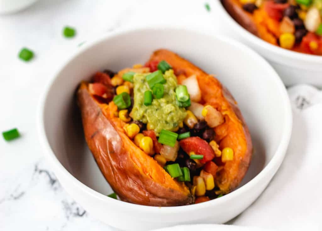 sweet potatoes stuffed with chili topped with guacamole and scallions