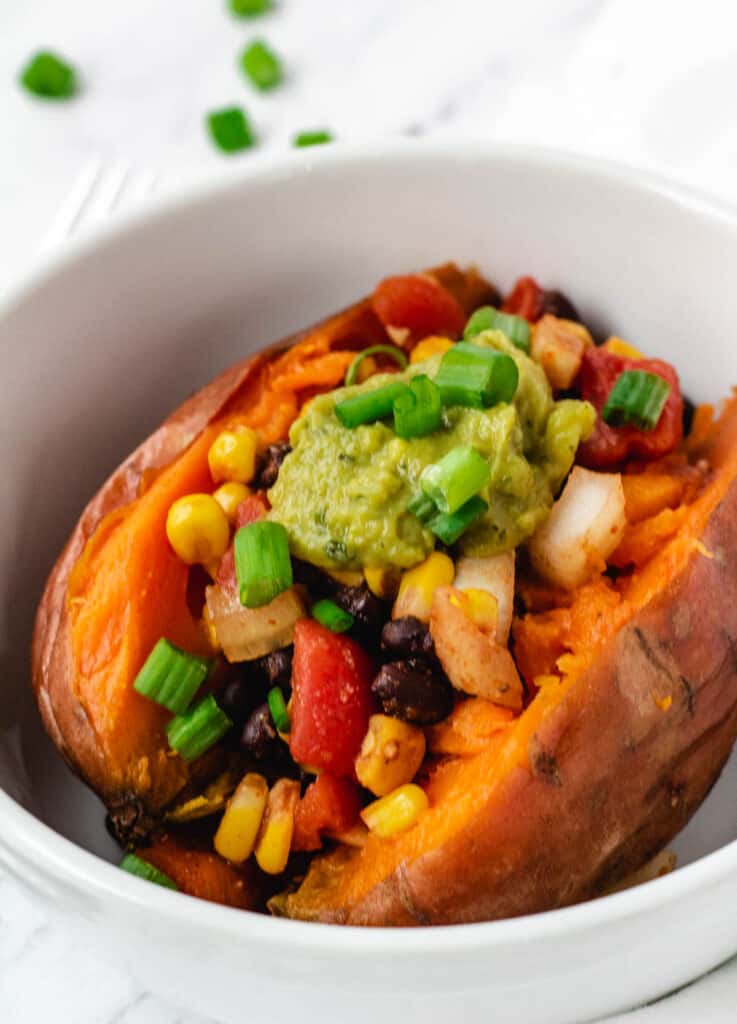 sweet potato stuffed with corn, black beans, onions, and tomato, topped with guacamole and scallions
