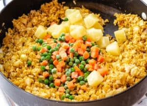 fried rice, peas, carrots, and pineapple in pan
