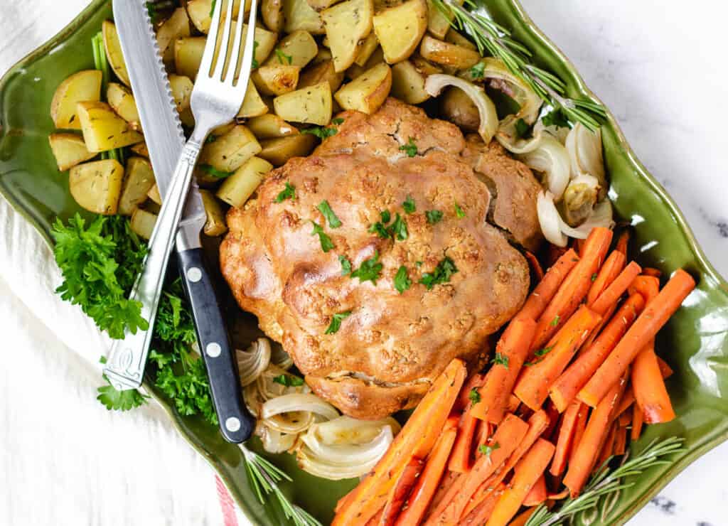vegan roast dinner platter with cauliflower, carrots, potatoes, onions, and herbs