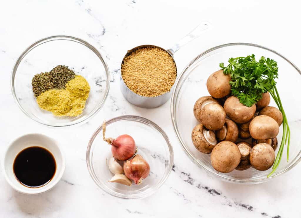 spices and herbs, soy sauce, breadcrumbs, shallots, garlic, mushrooms, and parsley in glass bowl