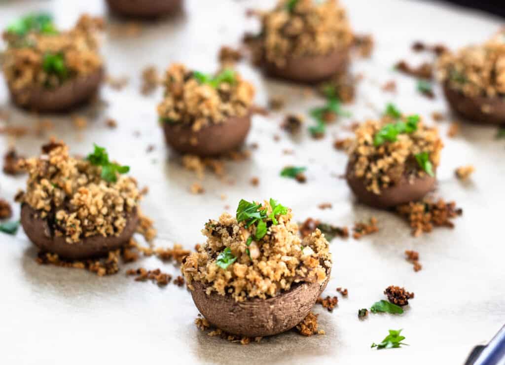 vegan stuffed mushrooms on parchment paper topped with parsley

