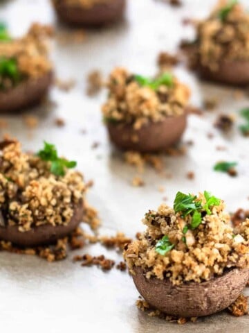 vegan stuffed mushrooms topped with parsley on parchment paper