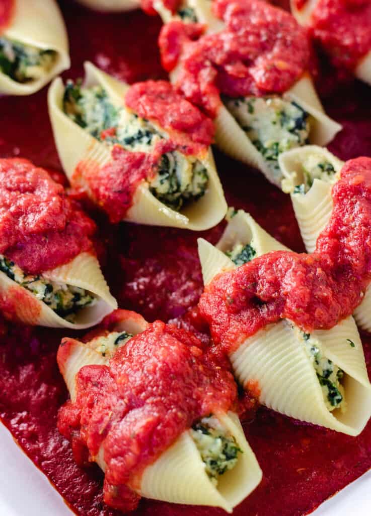 close up of vegan stuffed shells topped with tomato sauce