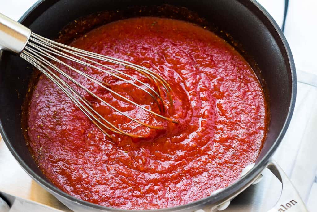 tomato sauce in pot with whisk