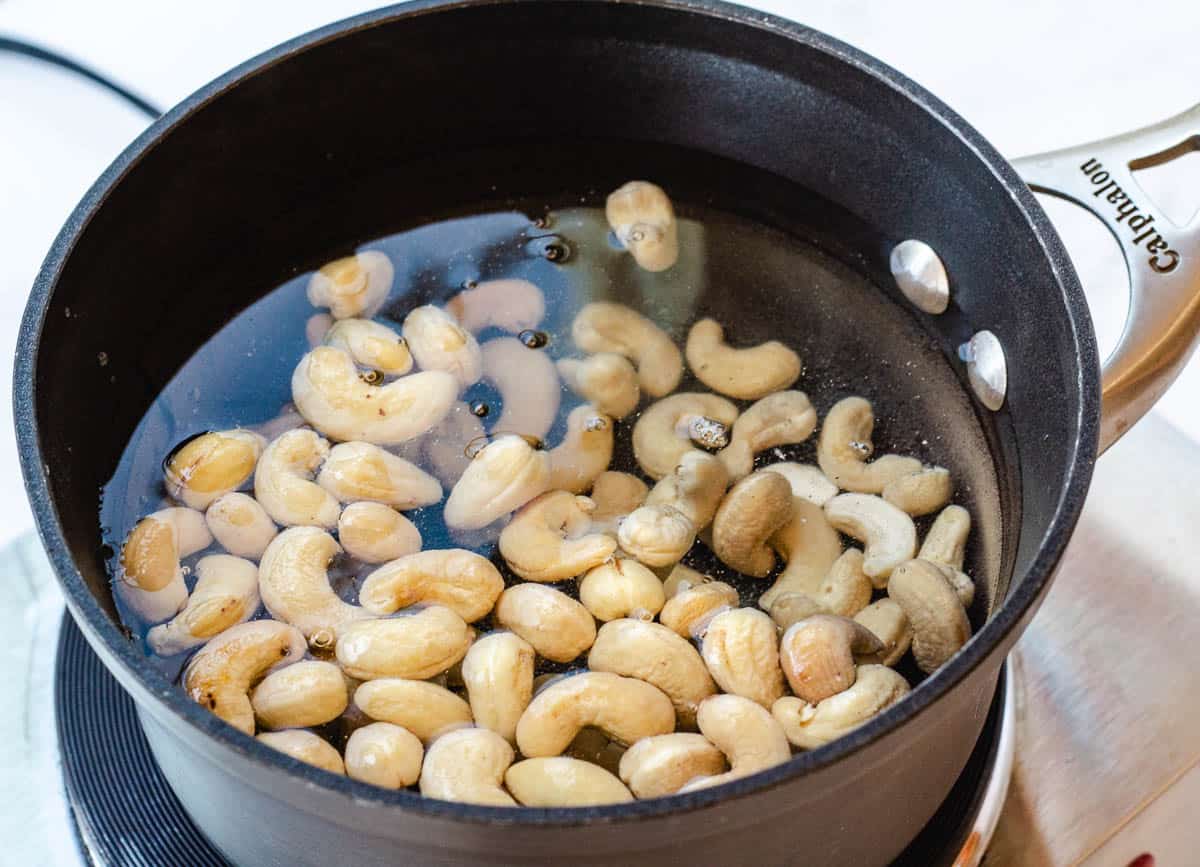 Cashews boiling in a pot of water.
