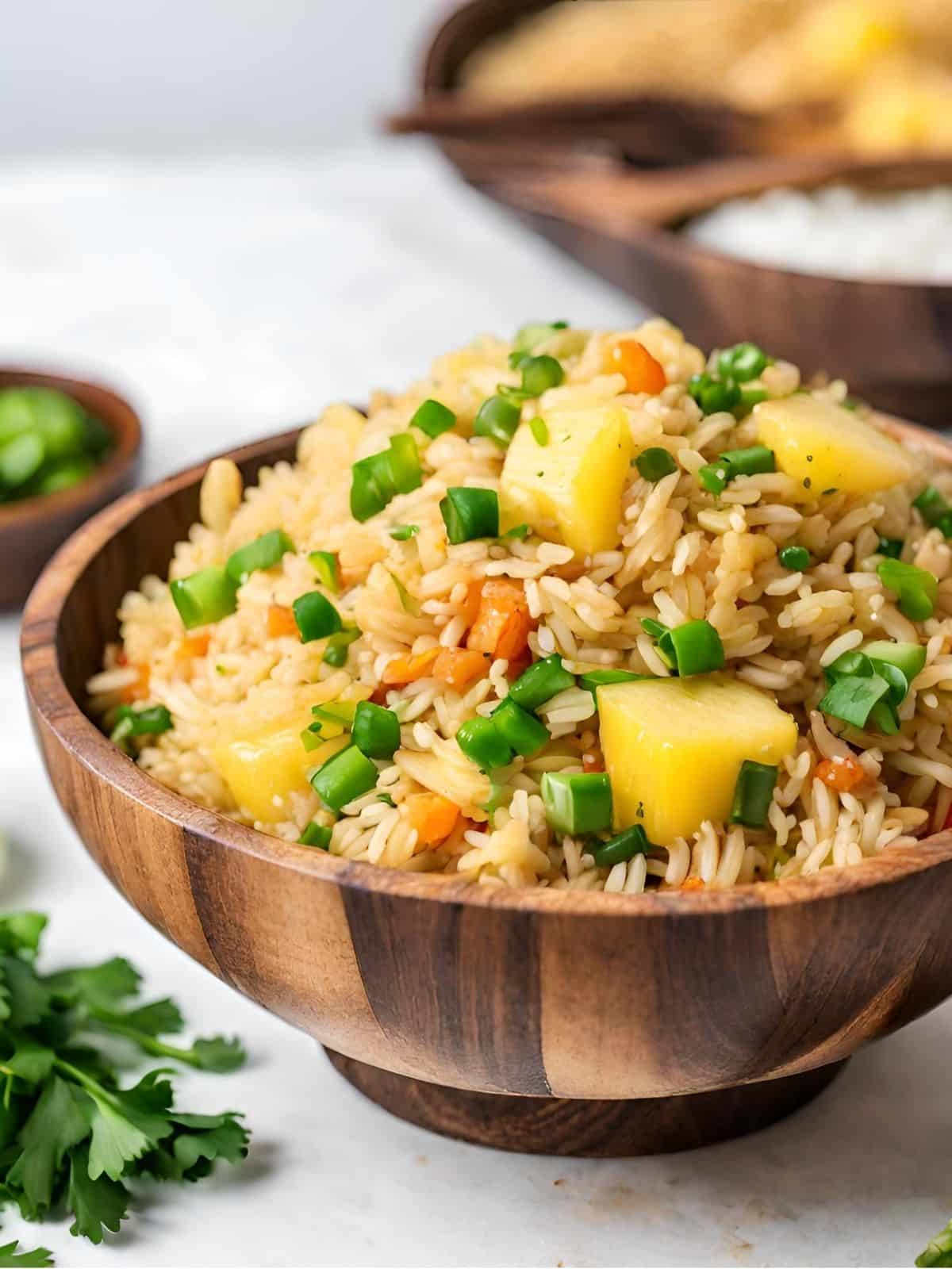 Vegan Thai fried rice with pineapple and green onions in a wood bowl.