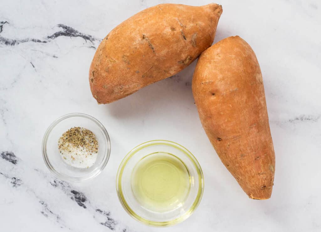 2 sweet potatoes, oil in glass bowl, and salt and pepper in glass bowl