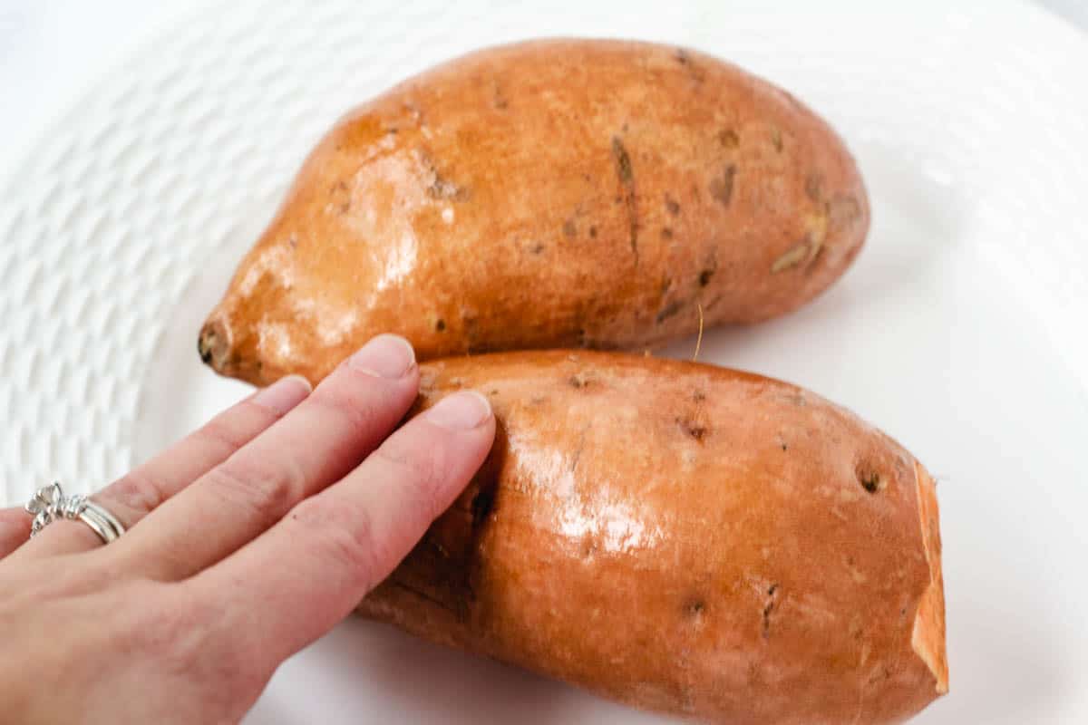 Hand rubbing oil on sweet potato skin.