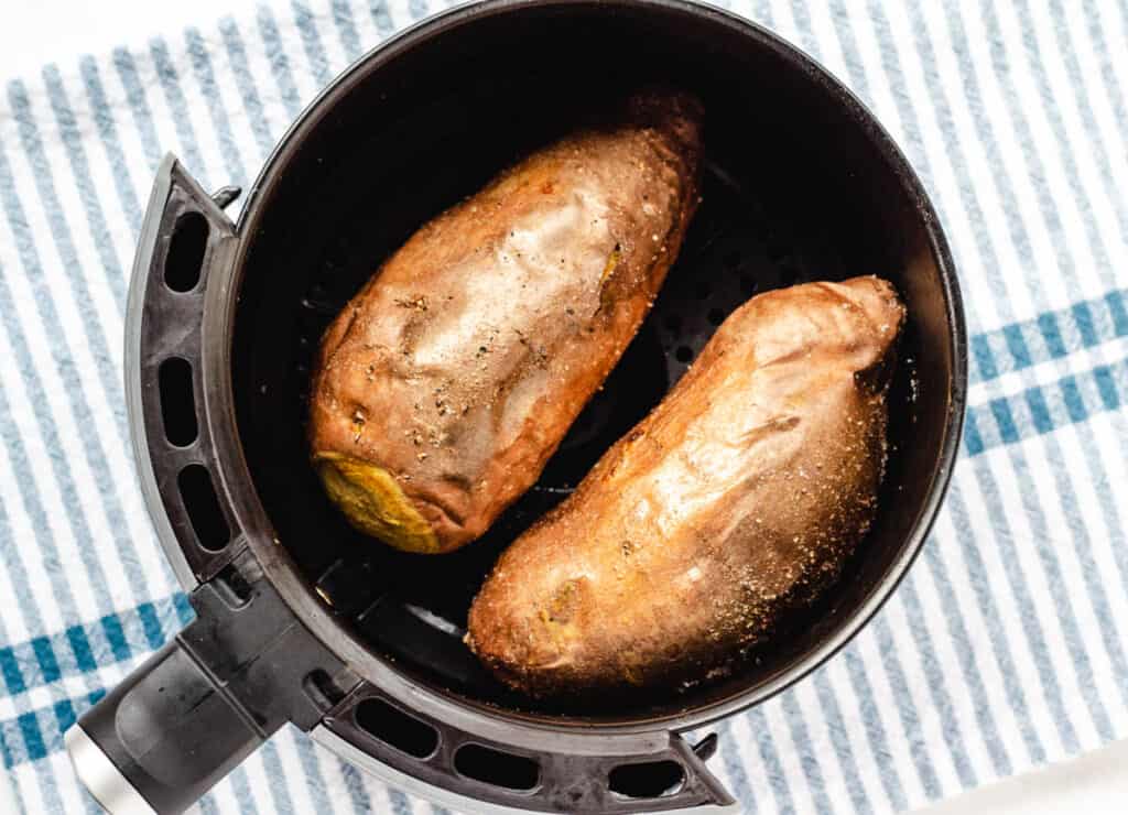 2 baked sweet potatoes in an air fryer basket