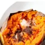 air fryer sweet potato in white bowl topped with butter and brown sugar