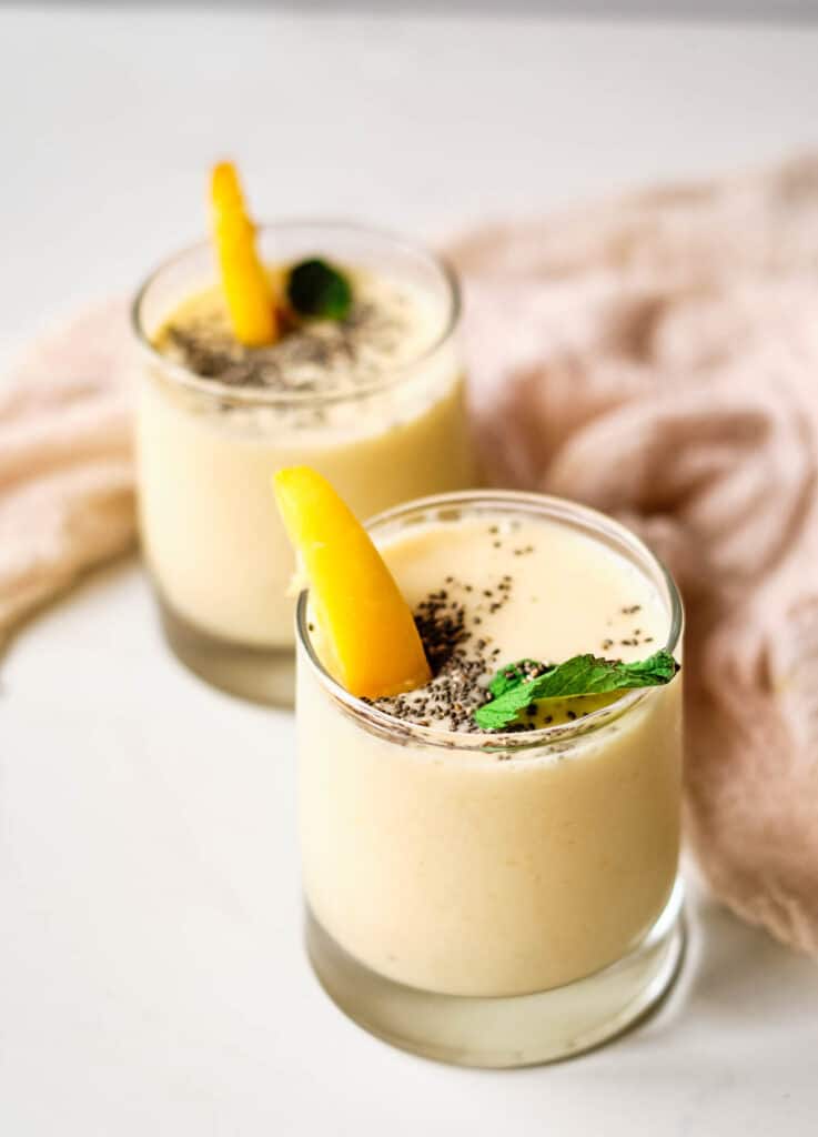 peach smoothies in glasses topped with chia seeds, mint, and peach slice