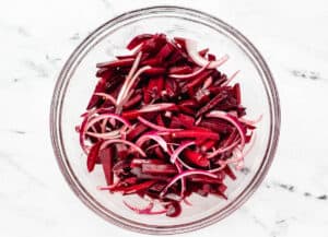 beet strips and red onion in glass bowl