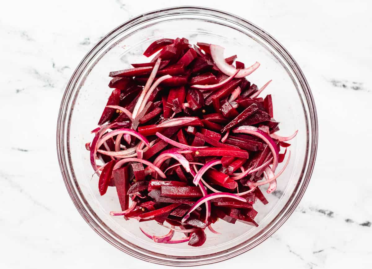 beetroot strips and red onion strips tossed together in glass bowl