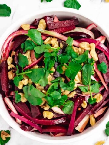 beetroot salad in white bowl topped with watercress