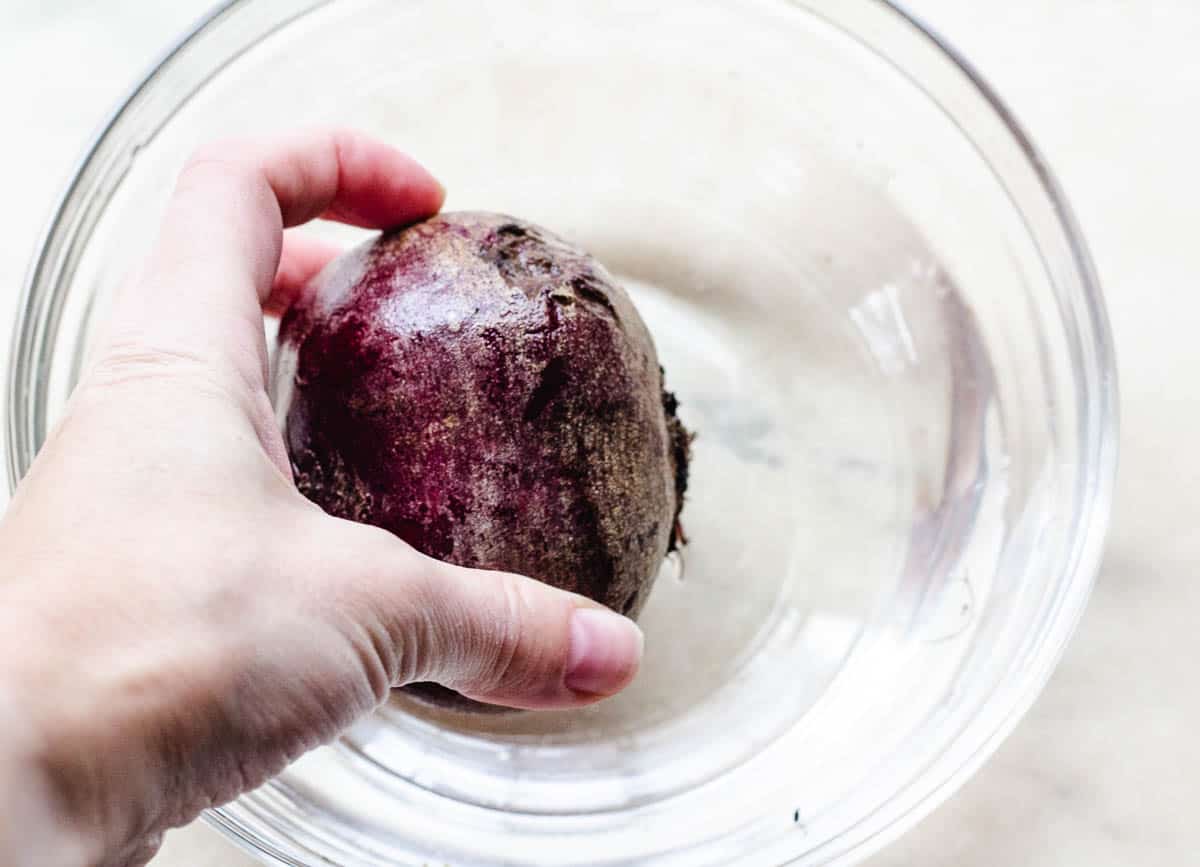 washing beetroot bulb in bowl of cold water